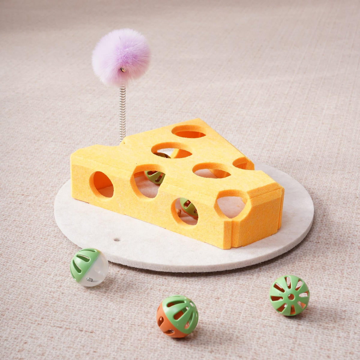 Yellow Hauloft cat puzzle box with pompom wand and bell balls, close-up