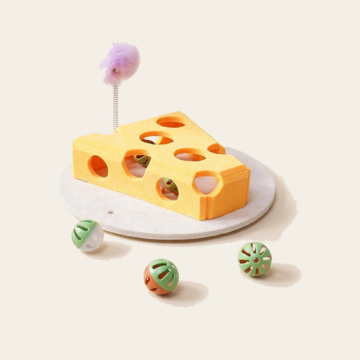 Cat Treat Puzzle Box with felt cheese, balls and spring wand on a plain sand background