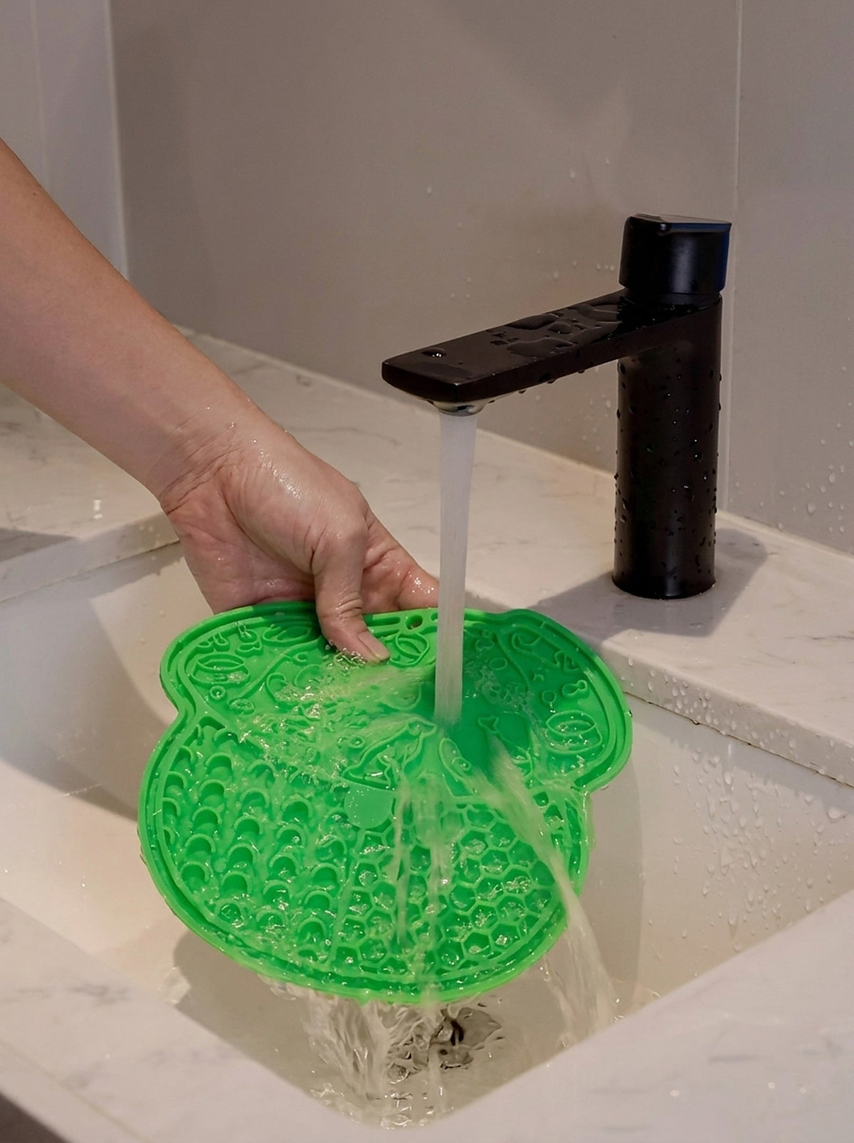 Rinsing the Hauloft lick mat under the tap