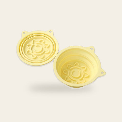 Yellow 3-in-1 collapsible travel dog bowls on a plain sand background